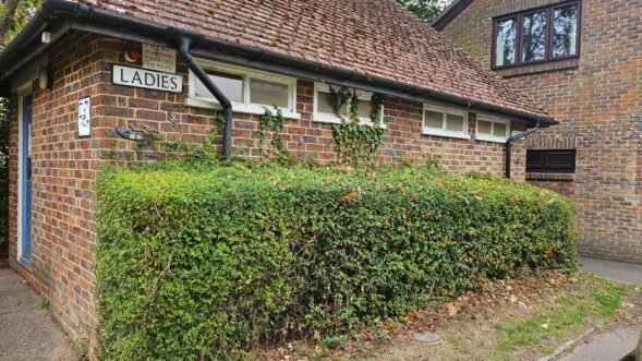 Brick toilet block viewed from Adastra car park with ladies, gents and disabled signs visible.